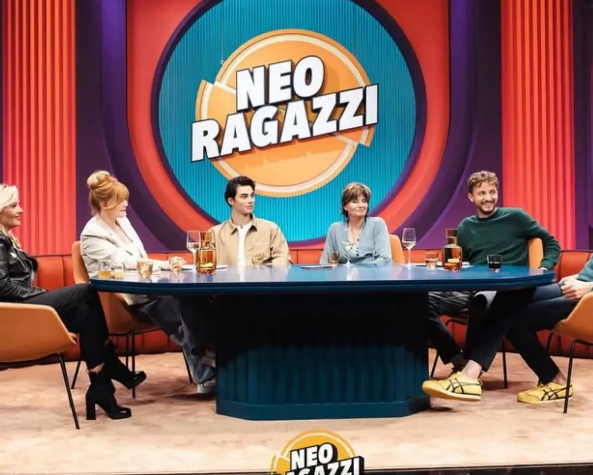 Eva Ries, Speakerin und Kulturjournalistin, sitzt als Gast in einer TV-Talkrunde vor dem Neo-Ragazzi-Studiohintergrund